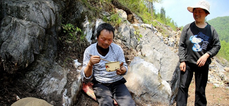 圖為曾付學的妻子陳滿英為他送午飯到山坡上，看著曾付學吃著自己做的可口飯菜，妻子露出笑容。